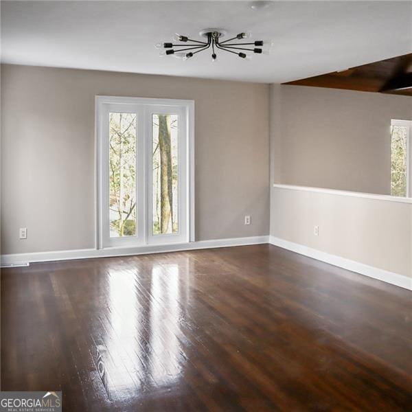 unfurnished room with a wealth of natural light, baseboards, and wood finished floors