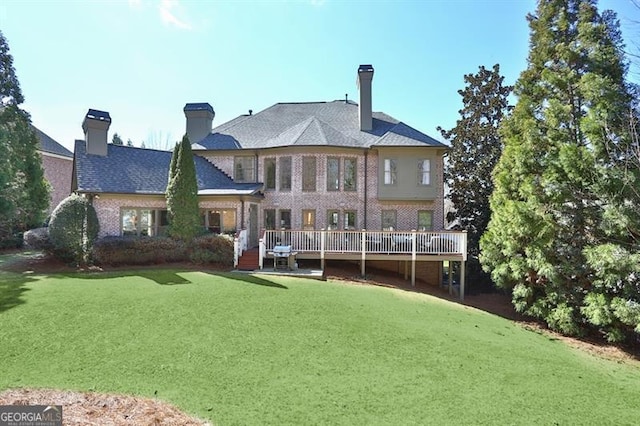 back of property featuring a deck, a yard, brick siding, and a chimney