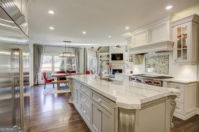 kitchen with dark wood-type flooring, a sink, backsplash, appliances with stainless steel finishes, and light stone countertops