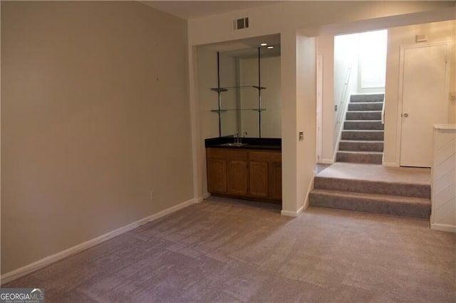 interior space with visible vents, baseboards, a sink, stairs, and light carpet