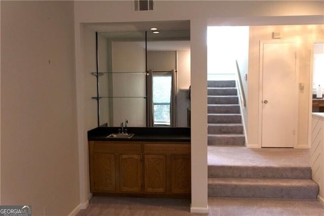 staircase with visible vents, wet bar, carpet, and baseboards