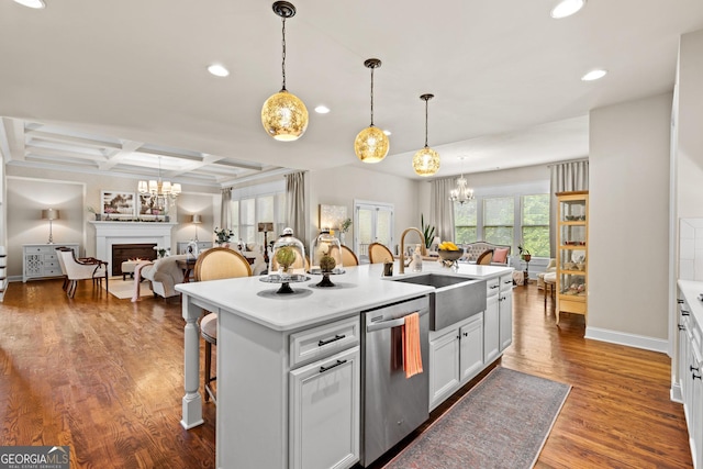 kitchen with a breakfast bar area, a warm lit fireplace, a sink, dishwasher, and a chandelier