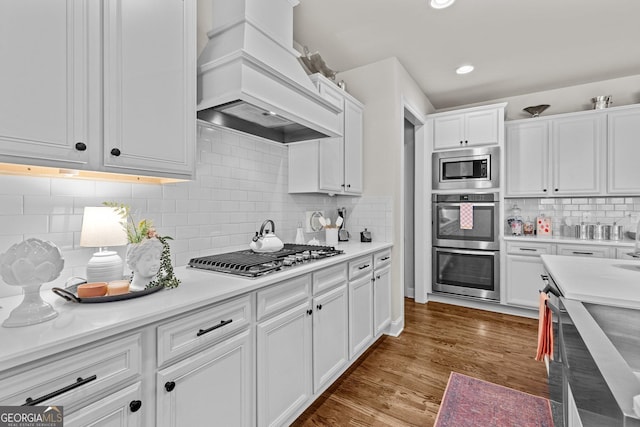 kitchen featuring light countertops, appliances with stainless steel finishes, wood finished floors, custom exhaust hood, and white cabinets