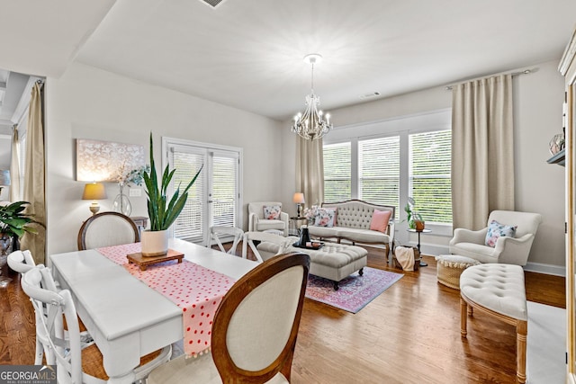 dining area with a notable chandelier, baseboards, visible vents, and wood finished floors