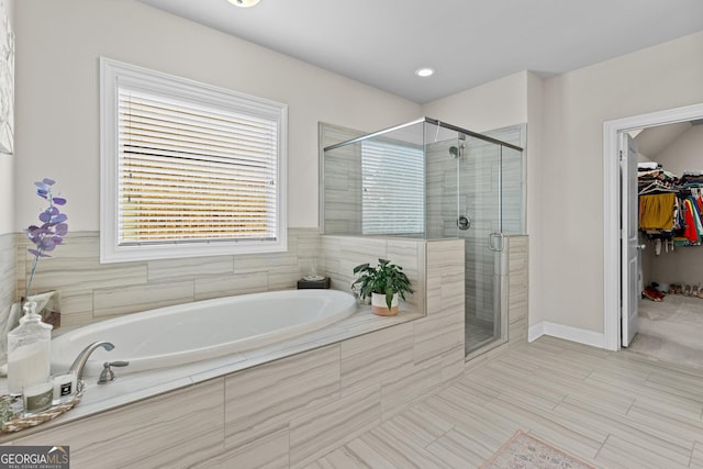 full bathroom featuring baseboards, a garden tub, a stall shower, and a spacious closet