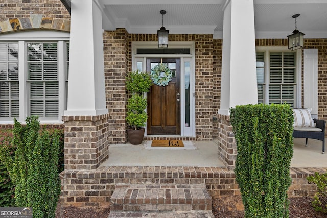 entrance to property with brick siding and a porch