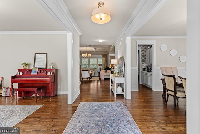 foyer entrance with a notable chandelier, dark wood-type flooring, and crown molding