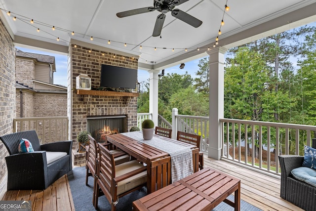 deck with outdoor dining area, a ceiling fan, and an outdoor brick fireplace