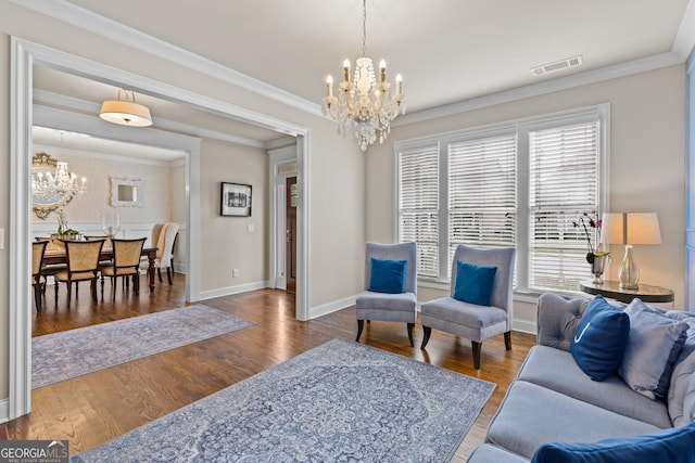 living room featuring visible vents, ornamental molding, wood finished floors, baseboards, and a chandelier