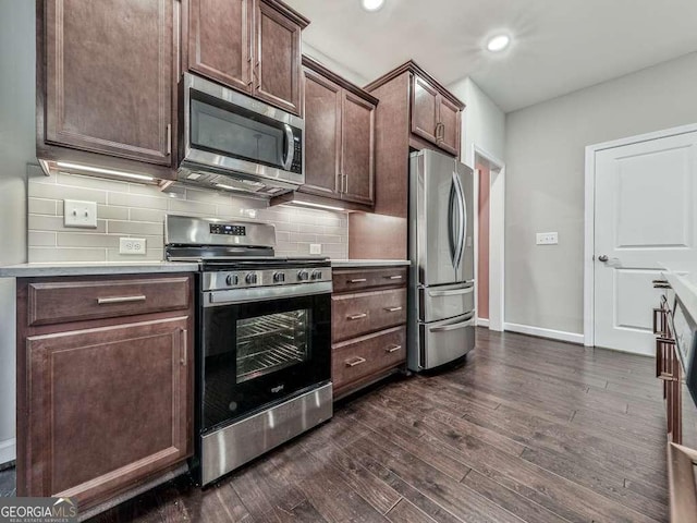 kitchen featuring dark wood-type flooring, tasteful backsplash, stainless steel appliances, dark brown cabinetry, and baseboards