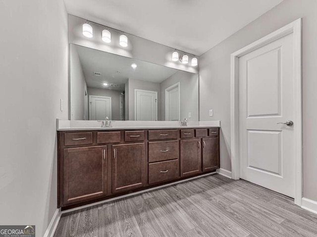 bathroom featuring a sink, baseboards, wood finished floors, and double vanity