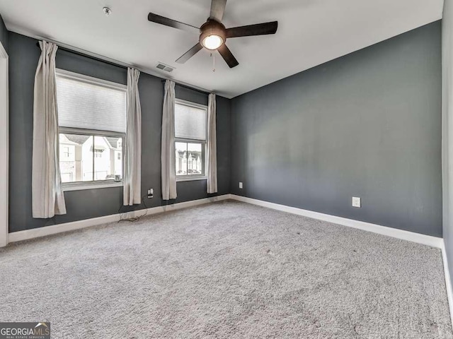 carpeted spare room featuring visible vents, ceiling fan, and baseboards