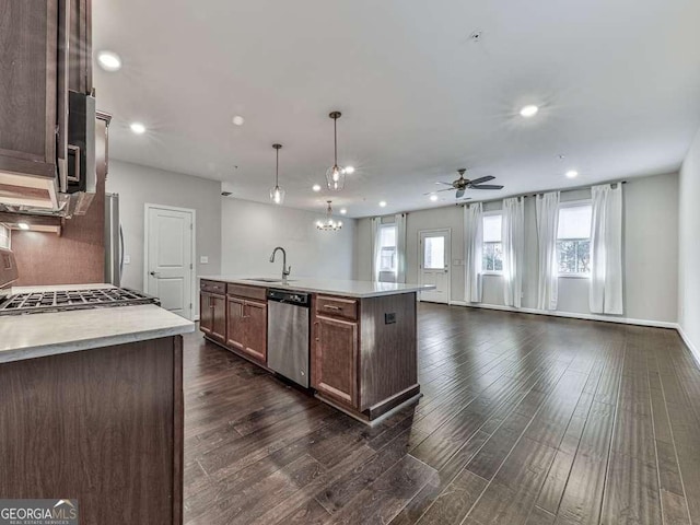 kitchen with stove, light countertops, dark wood-type flooring, stainless steel dishwasher, and open floor plan