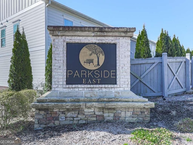 community / neighborhood sign featuring fence and a gate