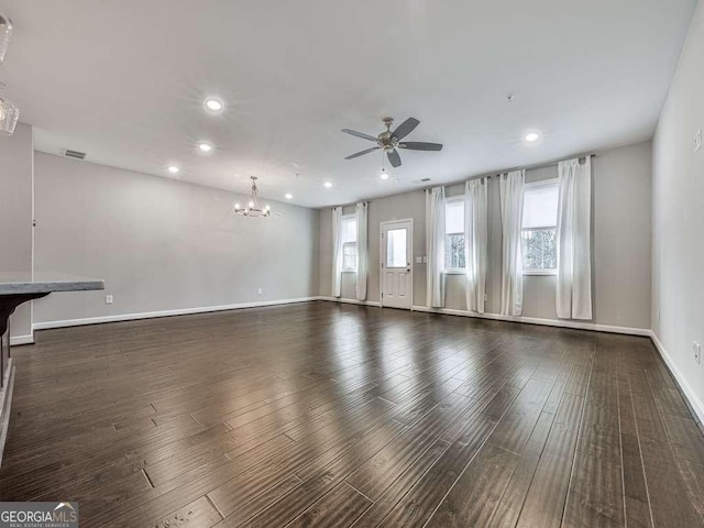 unfurnished living room with ceiling fan with notable chandelier, recessed lighting, wood finished floors, and baseboards