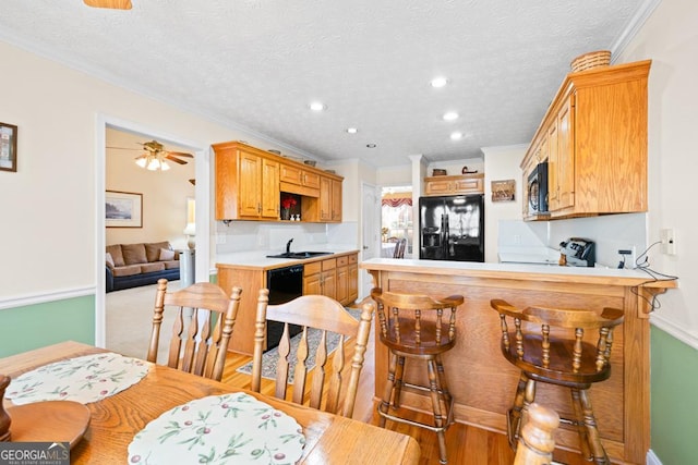 kitchen with a peninsula, a sink, black appliances, light countertops, and a textured ceiling