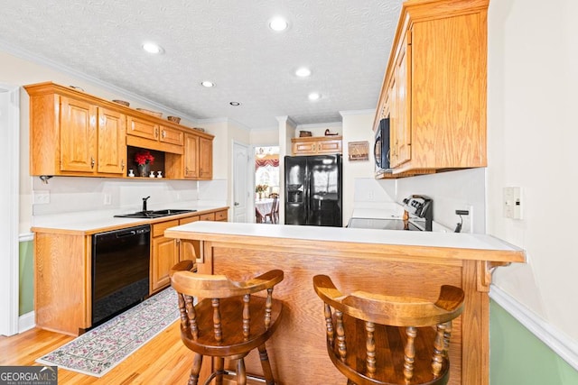 kitchen with black appliances, a sink, a textured ceiling, a peninsula, and light countertops