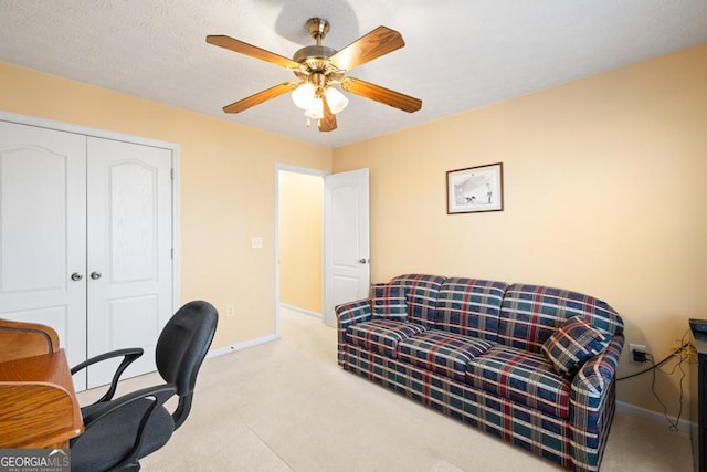 carpeted office with a textured ceiling, a ceiling fan, and baseboards