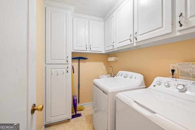 laundry room featuring a sink, cabinet space, a textured ceiling, and washing machine and dryer