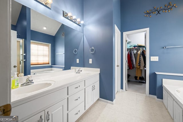 bathroom featuring double vanity, a garden tub, baseboards, and a sink