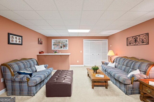 living room featuring carpet, baseboards, and a paneled ceiling