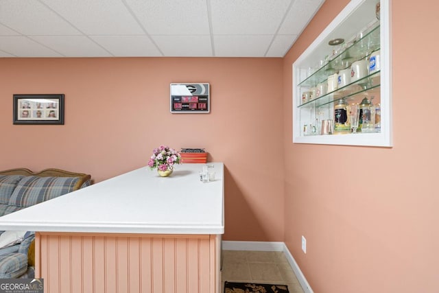 dining space with tile patterned floors, a paneled ceiling, and baseboards