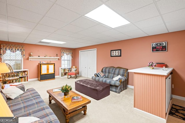 living room featuring baseboards, a paneled ceiling, and carpet flooring