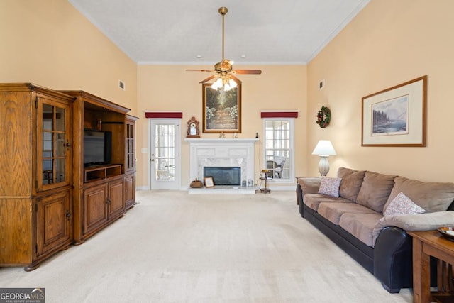 living area featuring crown molding, plenty of natural light, a fireplace, and light carpet