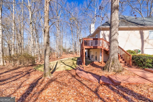 rear view of house featuring stairway, a wooden deck, and a chimney