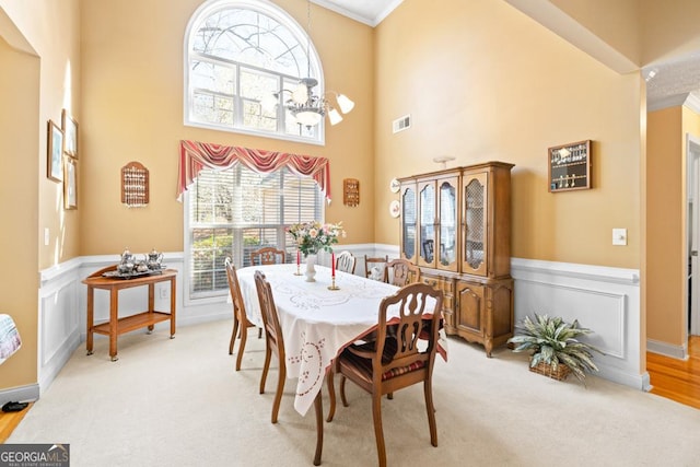 dining space featuring carpet floors, a notable chandelier, and wainscoting