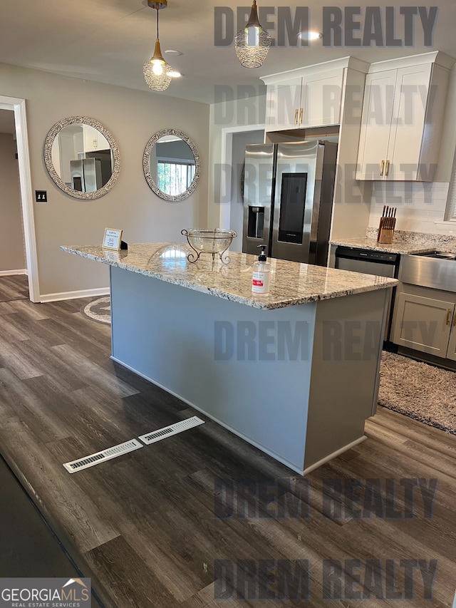 4025 Gretna Dr, Decatur, GA 30035 - kitchen featuring hanging light fixtures, dark wood finished floors, a center island with sink, light stone counters, and stainless steel appliances