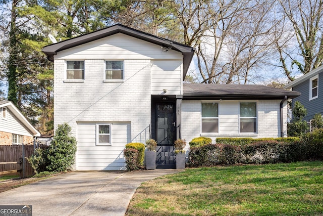 tri-level home featuring brick siding, a front lawn, and fence