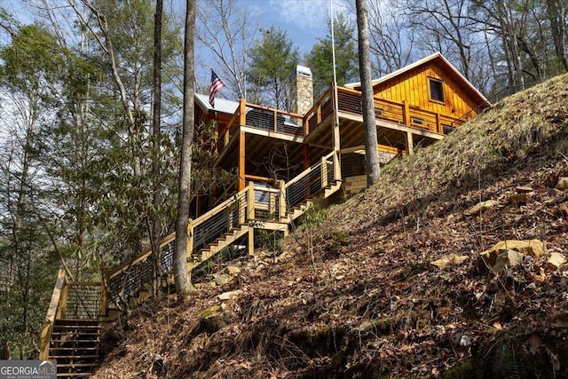 view of property exterior featuring a chimney, board and batten siding, and stairs