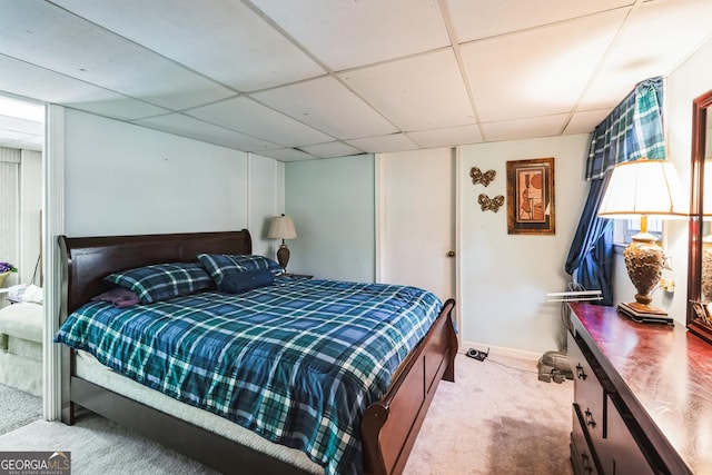 bedroom featuring a drop ceiling, baseboards, and carpet