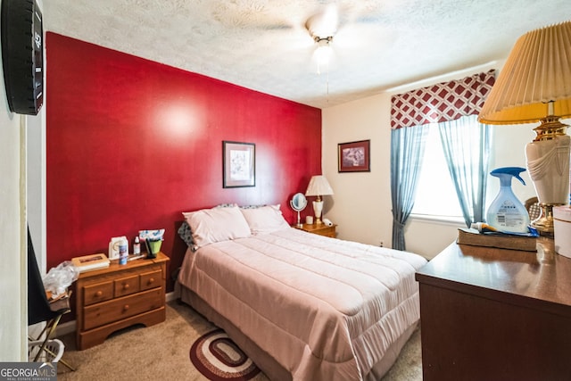 bedroom featuring light colored carpet, a textured ceiling, and a ceiling fan