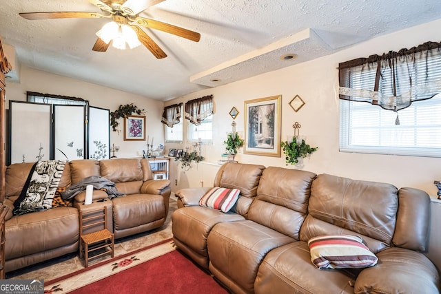 living area featuring a textured ceiling, a ceiling fan, and dark colored carpet