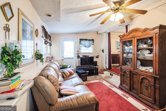 living area with a ceiling fan, a textured ceiling, wainscoting, and vaulted ceiling