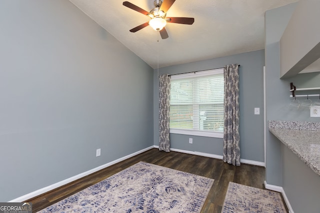 empty room featuring ceiling fan, baseboards, wood finished floors, and vaulted ceiling