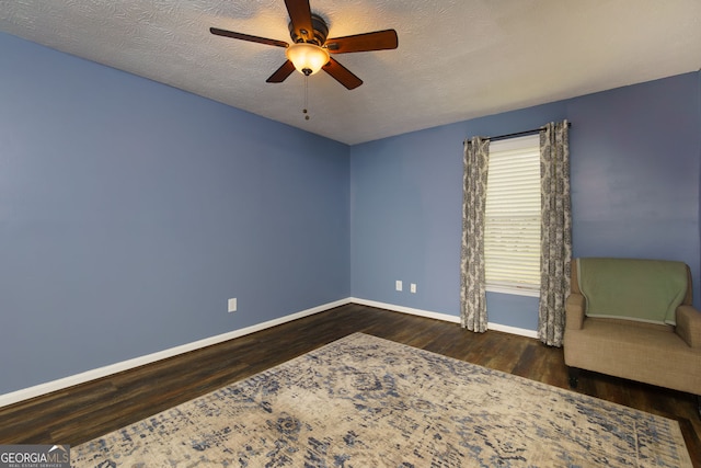 interior space with a textured ceiling, dark wood-type flooring, and baseboards