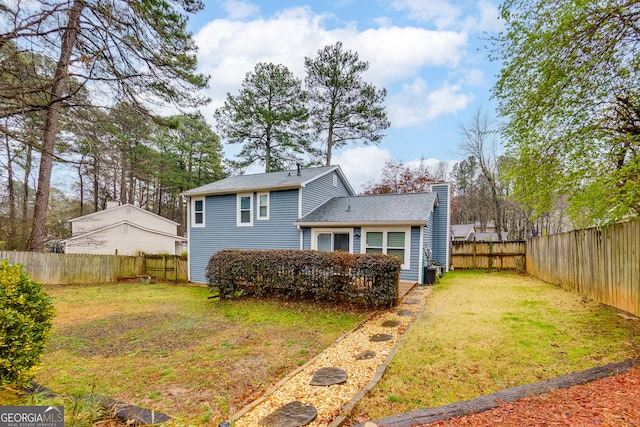 back of property featuring a lawn, a fenced backyard, and a chimney