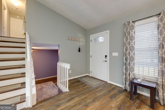 entryway featuring vaulted ceiling, stairs, baseboards, and wood finished floors