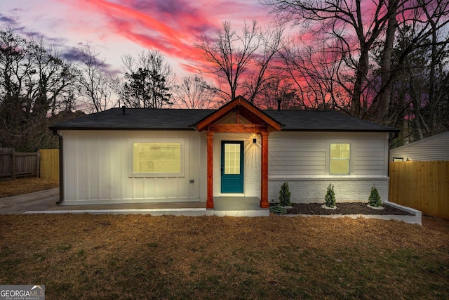 view of front facade with brick siding, a lawn, and fence