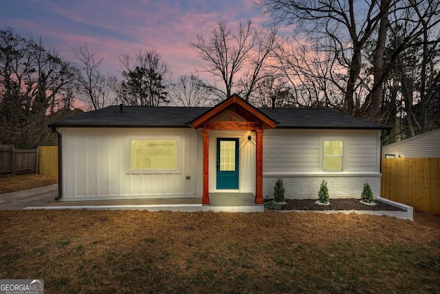 view of front of house with a front yard, fence, and brick siding