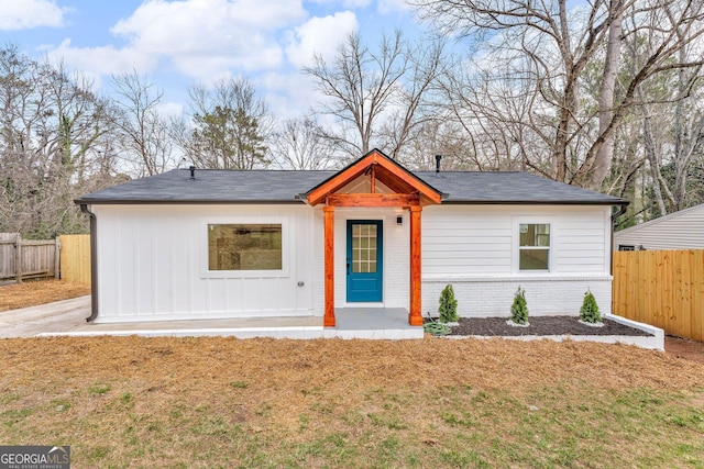 view of front of house with brick siding, a front yard, and fence