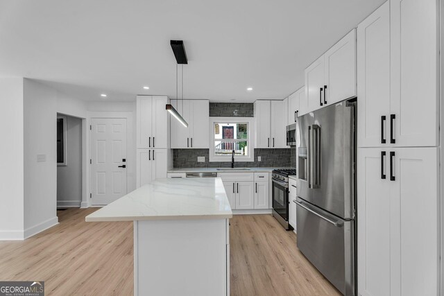 926 Natham Dr SE, Atlanta, GA 30315 - kitchen with backsplash, a sink, a center island, stainless steel appliances, and light wood-style floors