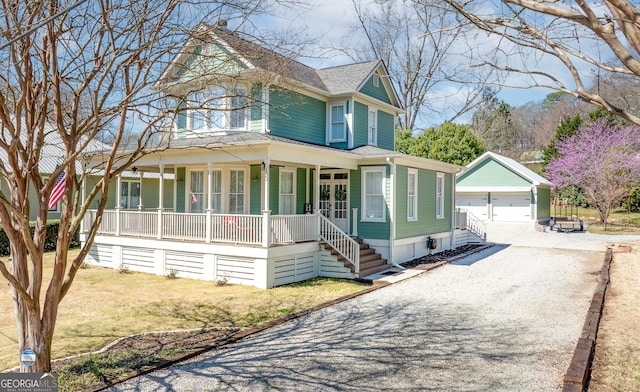 victorian-style house featuring a porch, an outbuilding, a front yard, and a detached garage