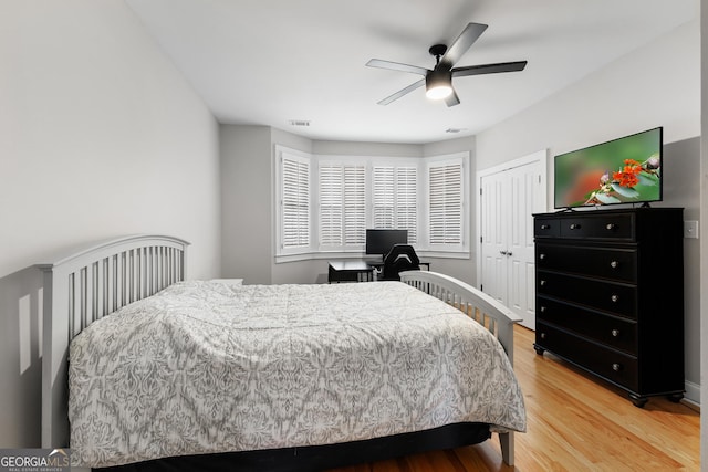 bedroom featuring a closet, visible vents, light wood-style flooring, and ceiling fan