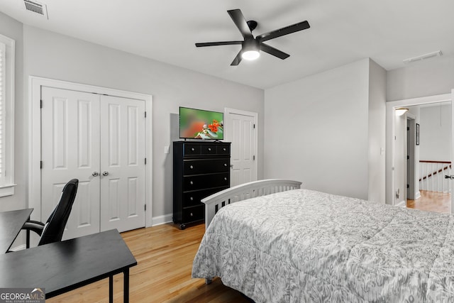 bedroom featuring two closets, visible vents, light wood-style floors, and a ceiling fan