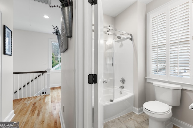 bathroom featuring toilet, shower / bathtub combination, and baseboards