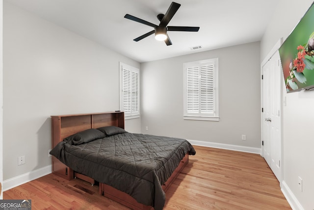 bedroom featuring visible vents, baseboards, wood finished floors, and a ceiling fan